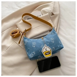 Detail of blue denim underarm bag with white bear print and yellow popcorn charm