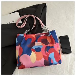 Detail of colorful geometric pattern tote bag with pink leather strap and metal chain