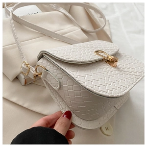 Close-up of ivory woven texture and gold metal clasp on a stylish crossbody bag