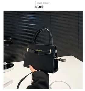 Détail du sac à main en cuir noir avec ferrures dorées et logo sur fond de stores