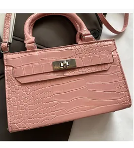 Detail shot of pink crocodile pattern handbag with metal turn-lock and sturdy feet