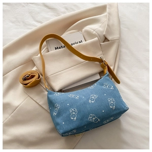 Detail view of printed denim underarm bag with cute bear pattern and yellow strap