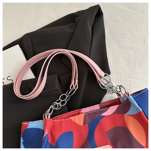 Detail of pink leather and silver chain strap on a colorful printed tote bag