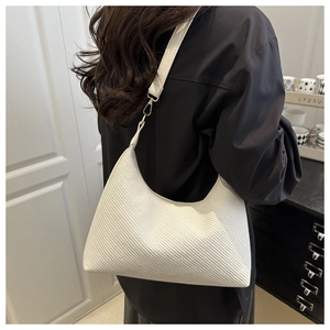 Detail view of white woven shoulder bag with faux crocodile strap and gold metal buckle