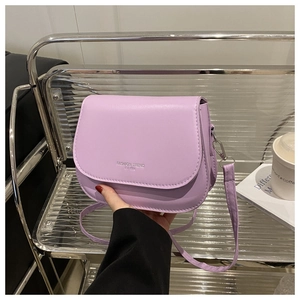 Close-up of light purple leather crossbody bag with Fashion Trend print on metal stand