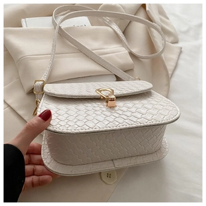 Macro shot of white woven texture and gold shield buckle on chic crossbody bag