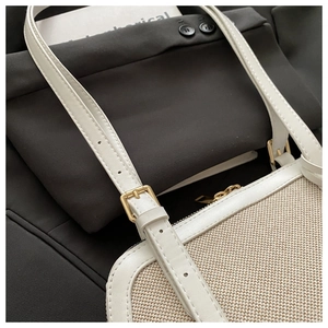 Close-up of beige canvas texture with white leather trim and gold hardware detailing