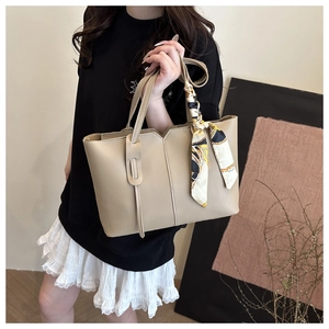 Detail view of beige PU leather tote bag with elegant silk scarf on handle for daily wear