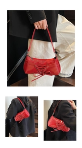 Detail view of red glossy crescent bag with ribbon laces and leather shoulder strap
