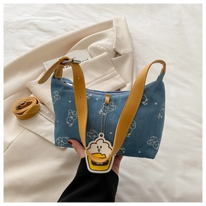 Detail of blue denim underarm bag with bear print and yellow faux leather strap