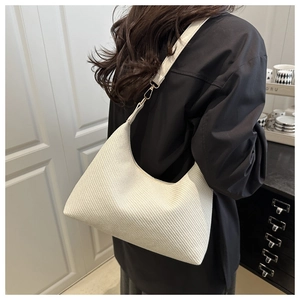 Detail of white woven hobo bag with gold buckle on shoulder of a female model