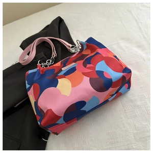 Detail of colorful geometric floral pattern and metal chain on a large tote bag