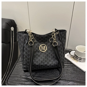 Detail of monogram tote bag with gold M logo, chain straps, and artistic interior styling
