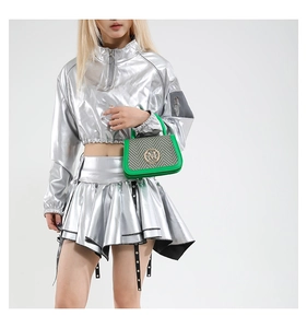 Detail of green handbag with metallic M logo paired with silver metallic outfit