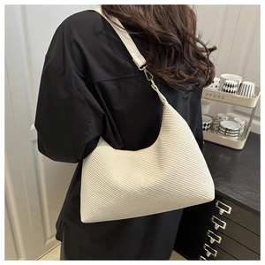 Close-up of cream hobo bag with twill texture and golden metal buckle detail