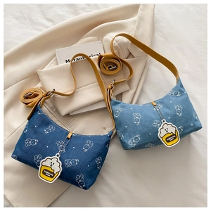Detailed view of denim shoulder bag with bear print and yellow leather strap with cake charm