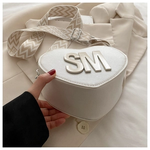 Detail of white heart-shaped PU crossbody bag with SM metal letters and woven strap