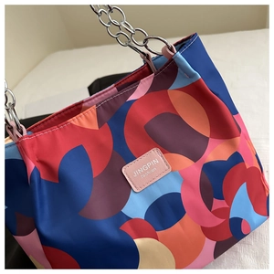 Detail of waterproof nylon tote with geometric patterns and silver chain handle