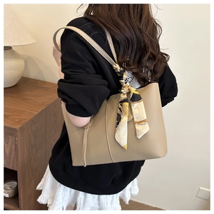 Detail of beige tote bag with long straps and floral scarf handle decoration