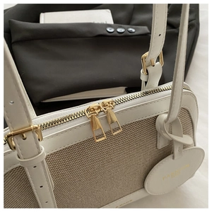 Detail of white canvas shell bag featuring gold zippers and premium leather trimming