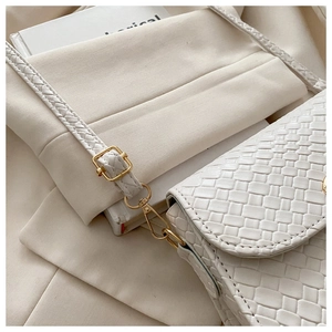 Detail of white woven texture shoulder bag with premium gold hardware and soft strap