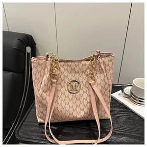 Detail of pink monogram tote bag with gold M logo and chain-leather handle on a desk