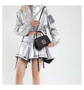 Detail of a black textured leather handbag with gold M logo on silver fashion outfit