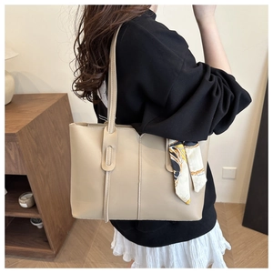 Detail of beige tote bag with fine stitching and decorative vintage pattern silk scarf