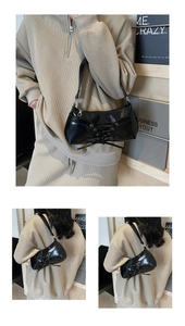 Detail of the black glossy PU shoulder bag featuring lace-up bow design and sleek strap
