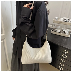 Detail shot of white textured tote bag featuring a minimalist design and elegant shoulder strap