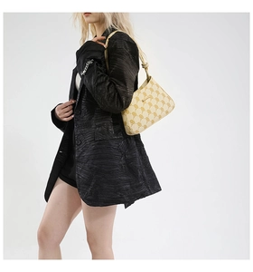 Dettaglio della borsa tote vintage con motivi indossata a spalla con blazer nero