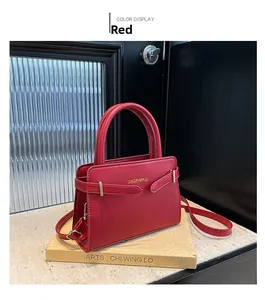 Détail du sac à bandoulière rouge en cuir avec sangle réglable et logo doré sur pierre