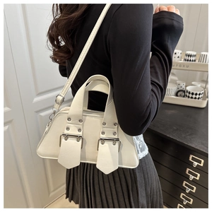Detailed side view of a white minimalist shoulder bag with decorative silver buckle straps