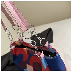 Detail of colorful printed tote with pink leather straps and silver metal chain links