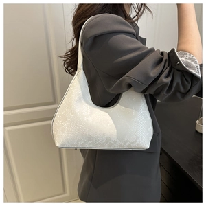 White snake pattern embossed hobo bag worn on shoulder over a grey blazer