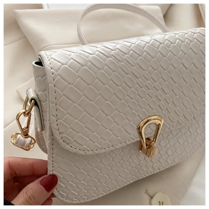 Close-up of white snake texture leather shoulder bag with golden metallic clasp and buckle