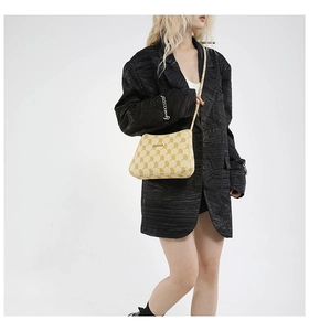 Détail du sac cabas beige avec imprimé chaîne et logo en métal sur modèle