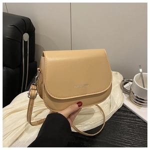 Detail of light apricot saddle bag with silver engraved logo and adjustable strap