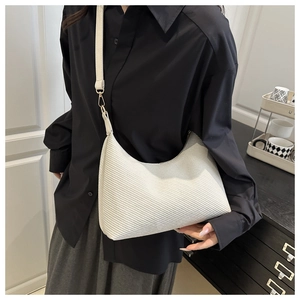 Gros plan du sac Hobo blanc avec texture diagonale et boucle en métal doré sur la sangle