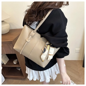 Detail of beige large tote bag with decorative silk scarf in a cozy home setting