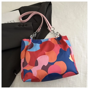 Detail of colorful geometric print tote bag with pink leather straps and metal rings