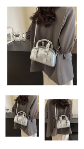 Close-up of a silver metallic bowling bag with dual handles and stylish buckle details
