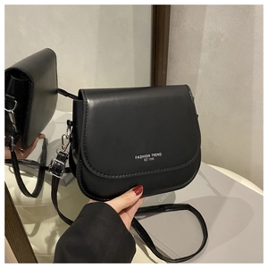Détail du sac selle en cuir noir avec imprimé texte blanc et boucle en métal argenté