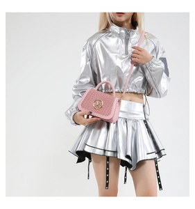 Close-up of pink leather handbag with red and white woven flap on silver metallic outfit
