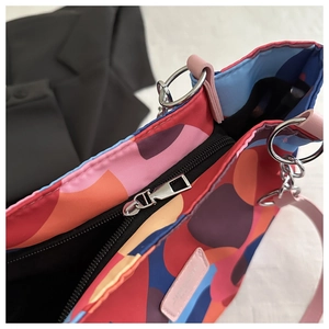 Detail of colorful abstract tote bag with zipper closure and metallic chain ring