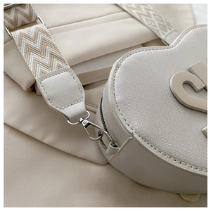Detailed close-up of heart-shaped white PU leather bag with texture and silver C logo