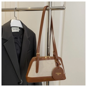 Detail of color-block canvas and leather handbag with metal zipper and hanging tag