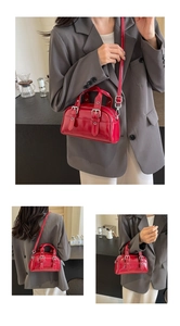 Macro detail of glossy red oil wax leather handbag with dual handles and metal buckles