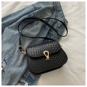 Detailed view of black woven texture on a square bag with golden horseshoe metal lock