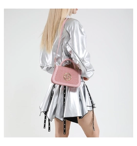 Pink and white woven crossbody box bag with gold M logo shown on a fashion model